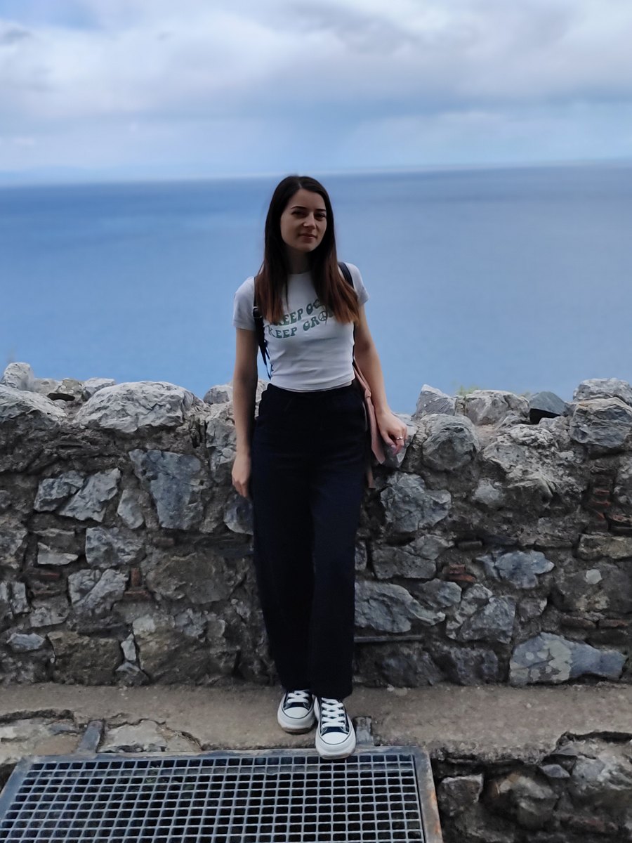 Claudia Sotîrca, farmacist diplomat, la un zid de piatră deasupra mării